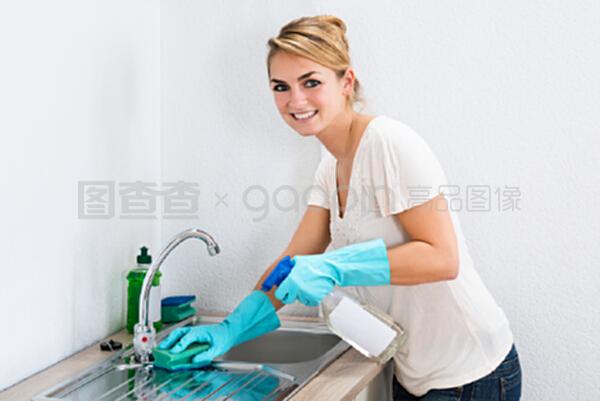 用海绵清洁厨房水槽的年轻妇女